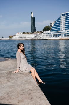 A woman is sitting in the water wearing a white dress. The water is calm and blue. The woman is enjoying the moment and taking in the beauty of the scene