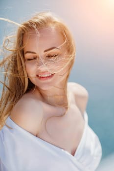 Portrait of a blond woman at the sea, a woman makes photos for memory from a trip to the sea to show to friends