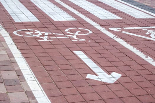 The image shows a white arrow on a bicycle lane, indicating a right turn. The road surface is made of asphalt, with rectangular and brickwork flooring