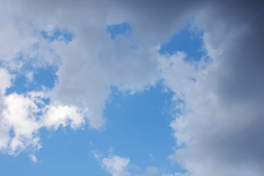 There is a sky filled with fluffy white clouds against a backdrop of electric blue. The scene also features a tree in the foreground creating a beautiful natural pattern