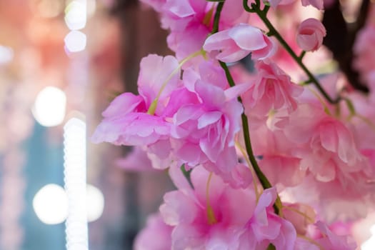 A cluster of vibrant pink flowers with glistening water droplets on their petals, blooming on a twig of a flowering plant in a garden