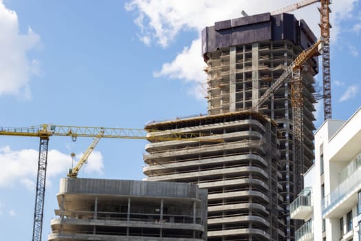 A tall skyscraper being built with a clear blue sky in the backdrop, showcasing urban design and modern engineering with a facade made of composite materials