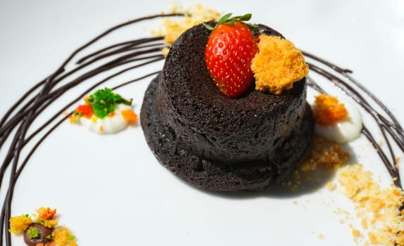 Delicious chocolate fondant or lava cake with cream, strawberry, and cake biscuit crumbles, Hot chocolate dessert pudding with liquid chocolate center, fondant au chocolate for cooking ideas and recipe