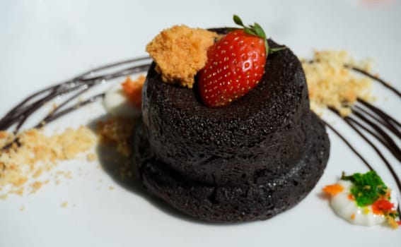 Delicious chocolate fondant or lava cake with cream, strawberry, and cake biscuit crumbles, Hot chocolate dessert pudding with liquid chocolate center, fondant au chocolate for cooking ideas and recipe