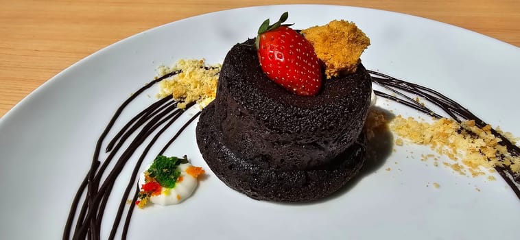 Delicious chocolate fondant or lava cake with cream, strawberry, and cake biscuit crumbles, Hot chocolate dessert pudding with liquid chocolate center, fondant au chocolate for cooking ideas and recipe