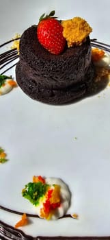 Delicious chocolate fondant or lava cake with cream, strawberry, and cake biscuit crumbles, Hot chocolate dessert pudding with liquid chocolate center, fondant au chocolate for cooking ideas and recipe