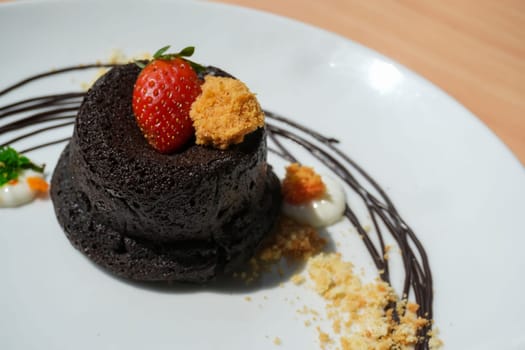 Delicious chocolate fondant or lava cake with cream, strawberry, and cake biscuit crumbles, Hot chocolate dessert pudding with liquid chocolate center, fondant au chocolate for cooking ideas and recipe