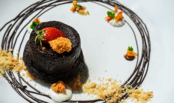 Delicious chocolate fondant or lava cake with cream, strawberry, and cake biscuit crumbles, Hot chocolate dessert pudding with liquid chocolate center, fondant au chocolate for cooking ideas and recipe