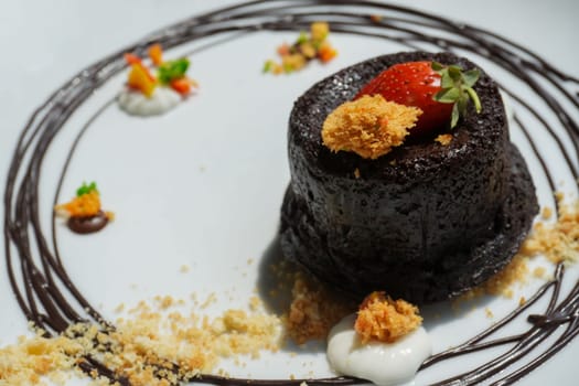 Delicious chocolate fondant or lava cake with cream, strawberry, and cake biscuit crumbles, Hot chocolate dessert pudding with liquid chocolate center, fondant au chocolate for cooking ideas and recipe