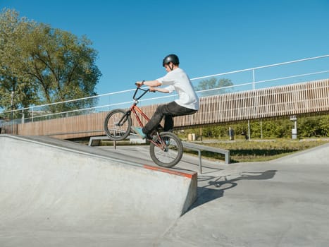 Skilled BMX rider performing Manual trick in ramp park. Young BMX bicycle rider having fun and posing in Manual Wheelie riding outdoors. Riding in back wheel in street park. Concrete street park