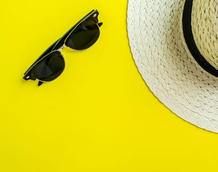 Flatlay, summer vacation. Straw hat and sunglasses on a yellow background. Background for advertising.