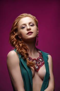 Studio photo of sexy redhead woman posing in jewelry