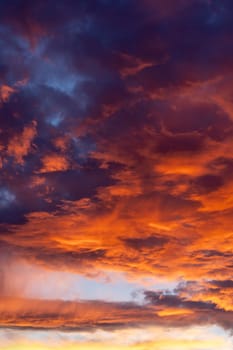 Dramatic fiery sky with dark red fluffy clouds, evening or morning dusk and golden sunlight