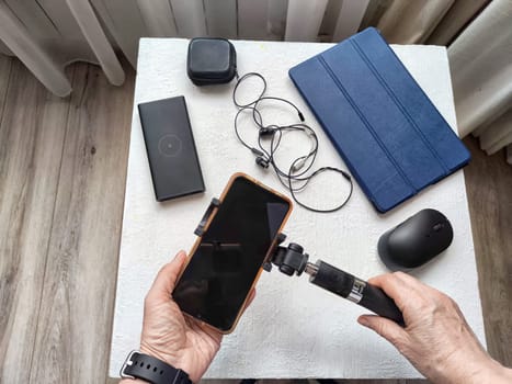 A set of useful blogger devices and hand of female blogger. A neatly organized desk featuring a smartphone, earphones, and various tech gadgets