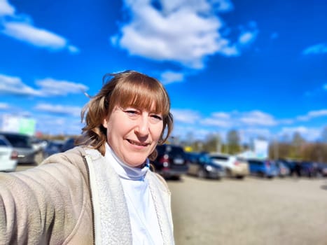 Middle aged Woman walks along the marking line on road by the car in sunny day. The concept of travel or journey