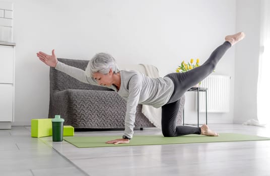 Calm Home Exercises In A Bright Room, A 70-Year-Old Woman Practices Yoga