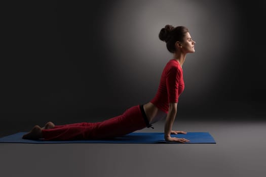 Pilates. Beautiful woman exercising in studio, on gray background