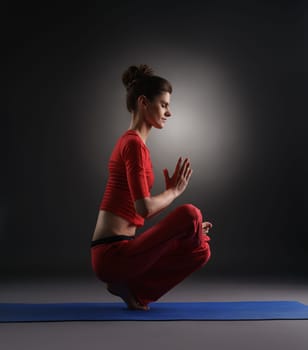 Yoga in studio. Woman doing asana, on gray background