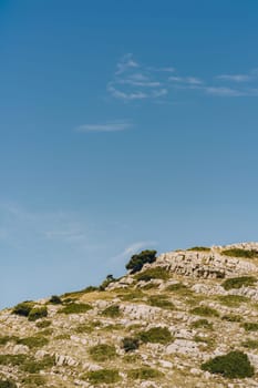 Rocky hill and clouds in blue sky, dramatic wild landscape of Dugi Otok island in Adriatic Sea, Croatia