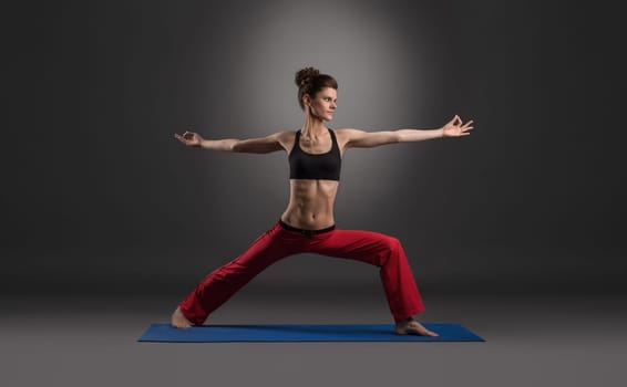 Woman practicing yoga in studio, on gray background