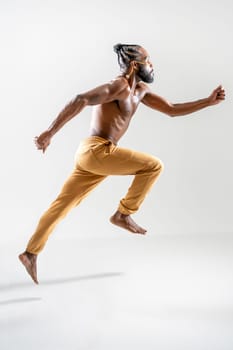 Full body of shirtless African American gay man running isolated on white background. Side view of muscular male runner jogging in white studio. Equality concept.