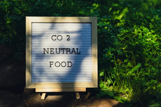 CO2 NEUTRAL FOOD message on background of fresh eco-friendly bio grown green herb parsley in garden. Countryside food production concept. Locally produce harvesting. Sustainability and responsibility
