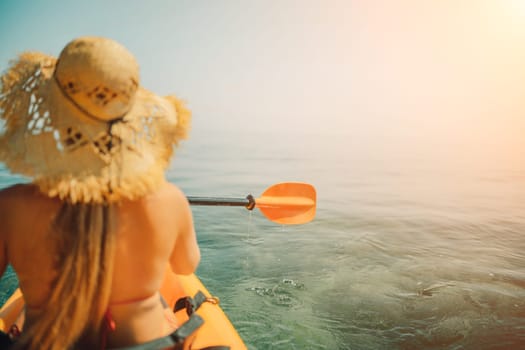 Woman in kayak back view. Happy woman with long hair in a swimsuit and hat floating in kayak on the sea. Summer holiday vacation. Summer holidays vacation at sea