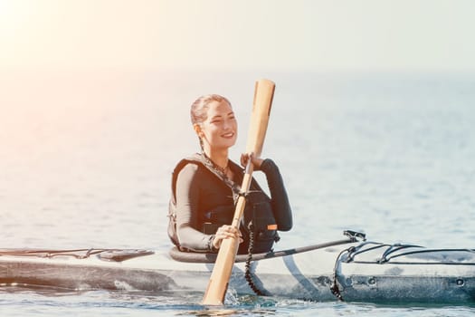 Happy smiling woman in kayak on ocean, paddling with wooden oar. Calm sea water and horizon in background