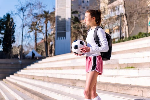 smiling caucasian woman walking at park with a soccer ball in hand, concept of sport and active lifestyle