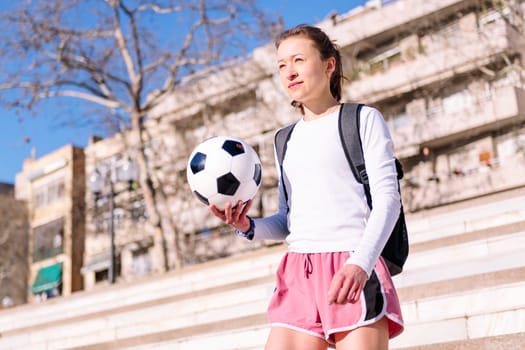 caucasian woman walking at city with a soccer ball in hand, concept of sport and active lifestyle, copy space for text