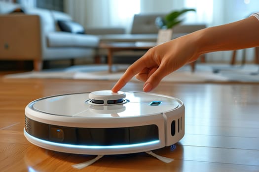 A woman's hand turns on a robot vacuum cleaner on the floor in the room.