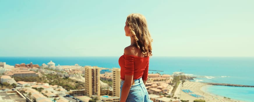 Summer vacation, beautiful young woman tourist on top of the mountain looking around the city in Tenerife, Canary Islands, Spain. Aerial top view.