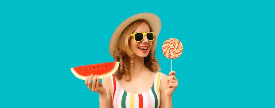 Summer portrait of happy young woman with lollipop or ice cream shaped slice of watermelon wearing straw hat on blue studio background