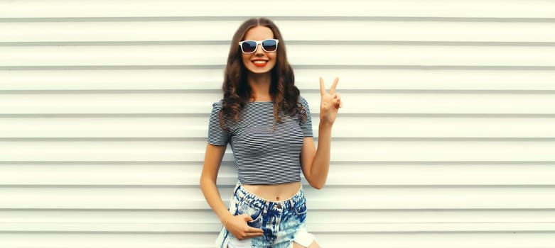 Stylish caucasian young woman posing wearing shorts and sunglasses on white background