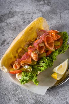 Smoked salmon sandwich on metal plate on stone table