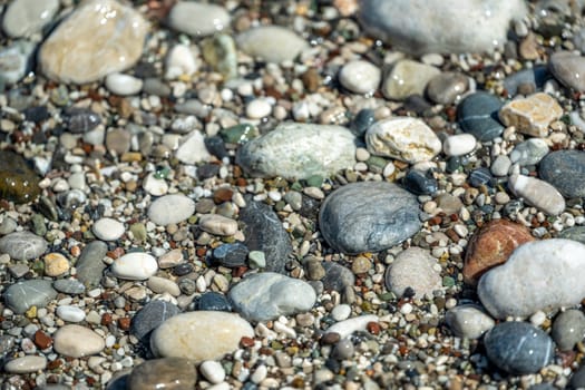 Beach with multicolored small round stones on a sunny day