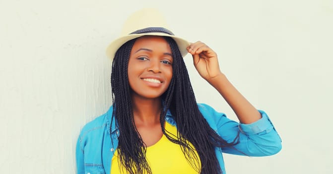 Portrait of stylish young african woman in summer hat with dreadlocks posing wearing casual in the city