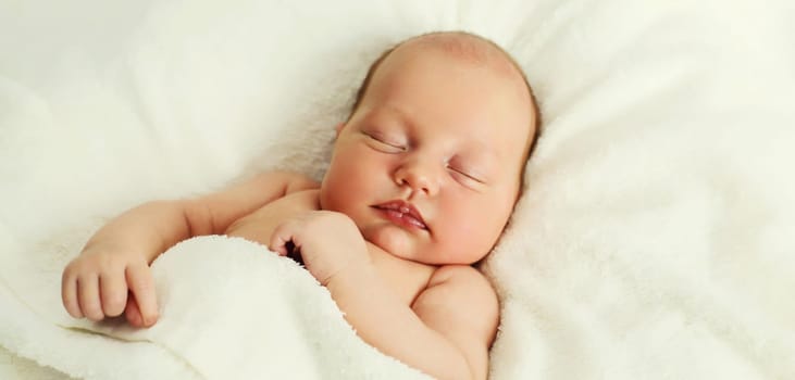 Close up portrait of infant sweet sleeping lying on white bed at home