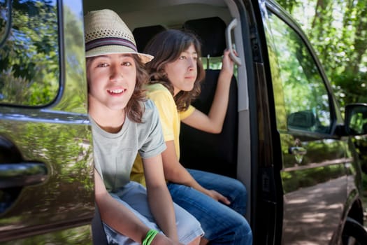 Two twin brothers are sitting in a van, one wearing a yellow shirt. They are smiling and seem to be enjoying their time together