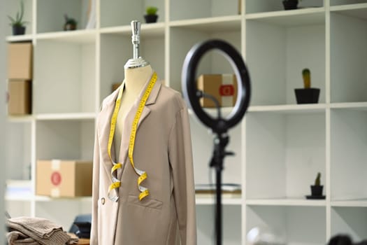 Mannequin with a beige suit and LED ring light in tailors studio. Small business and designer concept.