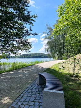 Sunny day and new bench near lake green trees. High quality photo