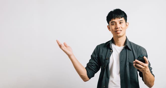 Portrait Asian smiling young man holding mobile phone and hand open to empty space studio shot isolated white background, Happy excited lifestyle men hold smartphone present something on palm