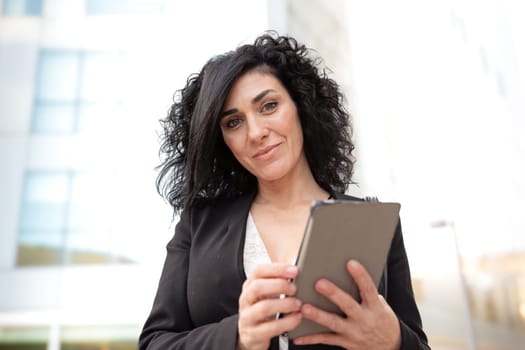 Portrait of a smiling middle-aged business woman with digital tablet in smiling hands looking at camera