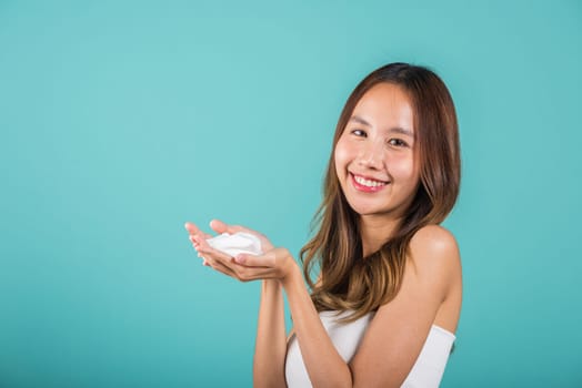 Portrait Asian young woman hands are adorned with white foam mousse studio shot isolated on blue background, beautiful female holding cleansing foam daily self care routine, beauty skincare concept