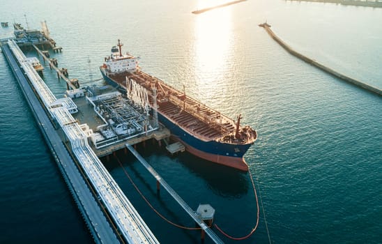 Aerial view of a large oil tanker docked at a pier in the port in process of loading.