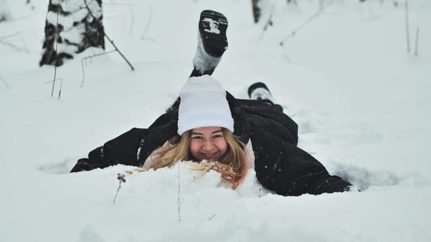 A girl falls on the snow in winter in the forest