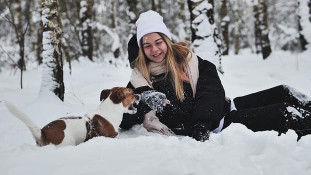 A girl playing with her Jack Russell Terrier dog in the snow