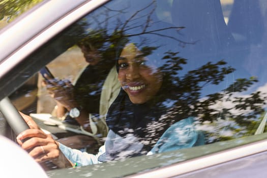 Two Muslim women wearing hijab converse on a smartphone while traveling together in a car through the.