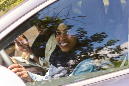 Two Muslim women wearing hijab converse on a smartphone while traveling together in a car through the.