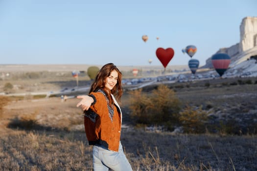 Woman admiring colorful balloons flying over field with distant castle view